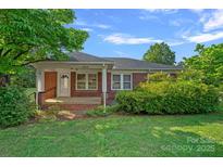 Charming single-story brick home featuring a cozy front porch and well-maintained landscaping at 1000 Peachtree Rd, Charlotte, NC 28216