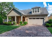 Charming home featuring stone accents, a well-manicured lawn, brick driveway and an attached two car garage at 10502 Old Ardrey Kell Rd, Charlotte, NC 28277