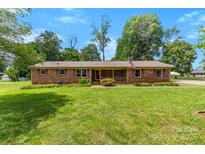 Charming brick home with well-manicured lawn, mature trees, and a cozy front porch at 113 Helena St, Mount Holly, NC 28120