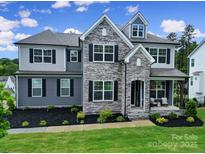 Charming two-story home featuring stone accents, a welcoming front porch, and well-maintained landscaping at 13222 Fiore Pl, Huntersville, NC 28078