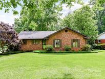 Charming single-story brick home featuring a well-manicured lawn and mature trees at 2401 Wensley Dr, Charlotte, NC 28210