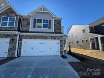 Two-story townhome features stone accents, a two-car garage, and an 'available' sign in the upper window at 4131 Black Ct # 170, Harrisburg, NC 28075