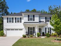 Charming two-story home featuring a white exterior, black shutters and a well-manicured front yard at 603 Southstone Dr, Matthews, NC 28104
