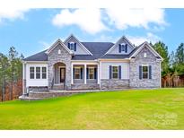 Stunning exterior view of a two-story home featuring stone accents, blue shutters, and a meticulously maintained lawn at 7517 Lancaster Hwy # 5, Waxhaw, NC 28173