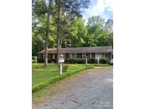 Charming one-story brick home with mature trees and a well-maintained front yard and driveway at 8524 Anette Ave, Mint Hill, NC 28227