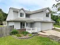 Charming two-story home featuring light siding, an attached garage and a well-manicured front yard and porch at 8540 Indian Summer Trl, Harrisburg, NC 28075