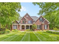 Stunning brick home featuring a meticulously manicured lawn with striped design and mature trees at 9918 Windrow Dr, Indian Trail, NC 28079