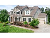 Charming two-story home with landscaped yard, stone accents, and welcoming front porch at 10911 Skymont Dr, Huntersville, NC 28078