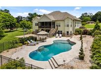 Backyard view of a large in-ground pool with lounge chairs and seating, set in a stone-paved area at 1115 Wynnbrook Way, Concord, NC 28027