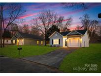 Charming single-Gathering home with green lawn and paved driveway at dusk at 1129 Thayer Glen Ct, Charlotte, NC 28213