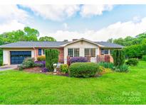 Charming one-story brick home with a well-manicured lawn, garden, and attached garage at 1184 Cambridge Dr, Shelby, NC 28152