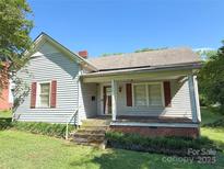 Charming home featuring a covered front porch, red shutters, and a well-maintained lawn at 125 Hunter St, Salisbury, NC 28144