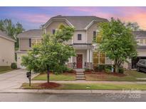 Charming two-story home featuring manicured landscaping, a welcoming front porch, and neutral toned siding and trim at 12832 Heath Grove Dr, Huntersville, NC 28078