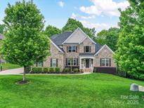 Stately brick home featuring a manicured lawn and mature trees, creating a welcoming curb appeal at 129 Overlook Ridge Ln, Davidson, NC 28036