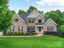 Charming two-story brick home with a manicured lawn and mature landscaping at 129 Overlook Ridge Ln, Davidson, NC 28036