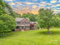 Charming two-story brick home boasts lush landscaping and a sprawling green lawn at 144 Chickasaw Dr, Shelby, NC 28152