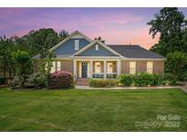 Charming brick home with a cozy front porch, colorful flowers, and lush green lawn at 161 Leaning Tower Dr, Mooresville, NC 28117
