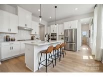 Bright, modern kitchen featuring white cabinets, stainless steel appliances, and a large island with seating at 3127 Beacon Heights Rd, Indian Land, SC 29707