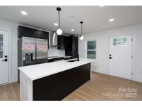 Modern kitchen featuring black cabinets, stainless steel appliances, and a large island with a white countertop at 4500 Ridgeley Dr, Charlotte, NC 28208