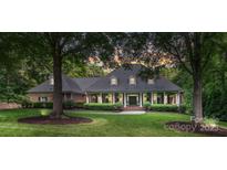 Charming brick home with manicured lawn, mature trees, and inviting front porch, perfect for relaxing evenings at 4920 Parview S Dr, Charlotte, NC 28226