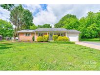 Charming single-story brick home featuring a well-manicured lawn and mature trees offering shade at 504 Forest Ridge Dr, Shelby, NC 28152