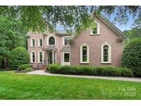 Charming brick home with manicured lawn, complemented by lush greenery and mature trees at 552 Wyndham Ln, Marvin, NC 28173