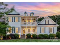 Stunning two-story home with a double porch, black shutters and a manicured lawn at dusk at 112 S Shore Dr, Belmont, NC 28012