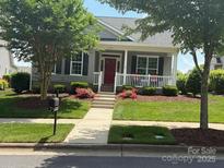 Charming single-story home features a well-manicured lawn, inviting front porch, and a vibrant red front door at 13318 Edenmore Ln, Cornelius, NC 28031
