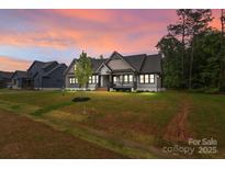 Picturesque home at dusk with manicured lawn, highlighting its inviting facade and neighborhood charm at 153 Mills Garden Rd, Statesville, NC 28625