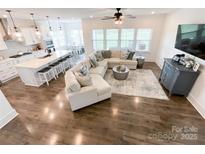 Open living room with hardwood floors, large sectional sofa, and view into the kitchen and breakfast nook at 2048 Turnsberry Dr, Monroe, NC 28112