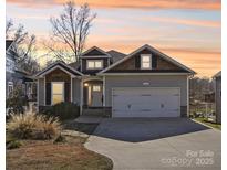Charming single-Gathering home featuring a well-manicured front yard, gray siding, and a two-car garage under a picturesque sunset at 21610 Rio Oro Dr, Cornelius, NC 28031