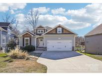 Charming home featuring a two-car garage, stone accents, beautiful landscaping, and a welcoming entrance at 21610 Rio Oro Dr, Cornelius, NC 28031