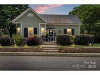 Charming home featuring a well-manicured lawn, stone retaining wall, and inviting front porch with dark shutters at 303 N Main N St, Granite Quarry, NC 28146