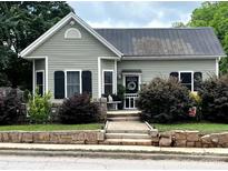Charming home featuring a stone entryway, manicured shrubs, and decorative black shutters at 303 N Main N St, Granite Quarry, NC 28146