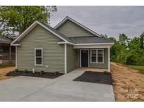 Charming home with light green vinyl siding, black roof, and freshly landscaped front yard at 407 Chambers St, Statesville, NC 28677