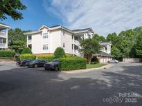 Three-story condo building with white siding, garages, and manicured landscaping on a partly cloudy day at 8747 Coralbell Ln, Charlotte, NC 28213