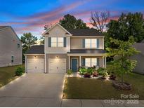 Charming two-story home with a well-manicured lawn, a two-car garage, and a welcoming front porch at sunset at 9132 Colwick Hill Ln, Charlotte, NC 28215