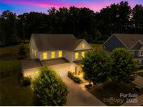 Stunning two-story home with a three-car garage and manicured lawn, brightly lit at dusk at 10901 Greenvale Dr, Harrisburg, NC 28075