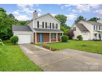 Charming two-story home with a brick facade, gray siding, lush green lawn, and private driveway at 2903 Rockingham Sw Ct, Concord, NC 28025