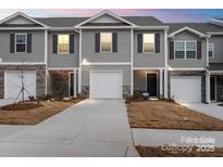 New townhome showing garage, stone accents, neutral paint, and a manicured lawn at 4116 Lurelin Ln, Charlotte, NC 28262