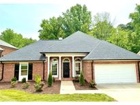 Charming brick home featuring a well-manicured lawn, complemented by a two car garage and a stylish, columned entryway at 456 Brook Valley Ne Ct, Concord, NC 28025
