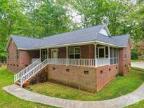 Charming brick home featuring a large front porch with white railings, surrounded by mature trees and landscaping at 4620 Binwhe Ln, Gastonia, NC 28052
