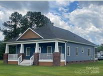 Charming blue home with a covered front porch, white columns, and manicured lawn at 6650 Highway 341 Hwy, Kershaw, SC 29067