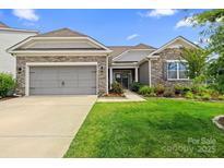 Charming home featuring a stone facade, manicured lawn, and an attached two-car garage at 7016 Bareland Rd, Fort Mill, SC 29707