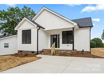 New construction home features white siding, black framed windows and a concrete driveway at 705 Sunderland Sw Rd, Concord, NC 28027