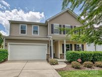 Tan two-story home with a two-car garage, and well-maintained landscaping at 9027 Gray Willow Rd, Charlotte, NC 28227