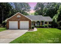 Charming brick home featuring a well-manicured lawn, attached garage, and cozy front porch at 1014 Covewood Ct, Charlotte, NC 28270