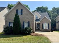 Charming two-story brick home with manicured lawn, black shutters, and a basketball hoop over the driveway at 1043 Cambrook Ct, Concord, NC 28027