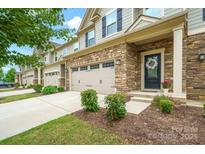 Charming townhome featuring stone accents, two-car garage, and an inviting front entrance with well-manicured landscaping at 117 Lanyard Dr # E, Mooresville, NC 28117