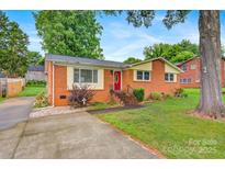 Charming brick home with a red door, landscaped yard, and long concrete driveway at 1405 8Th Nw Ave, Conover, NC 28613